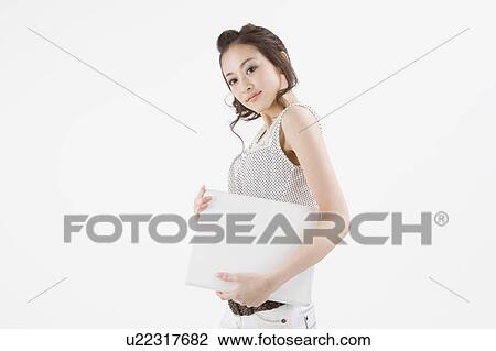 Stock Image - Young woman holding notebook computer. Fotosearch