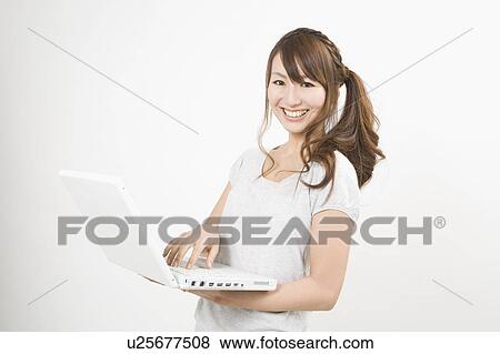 Young woman holding notebook computer View Large Photo Image Stock Photo - Young woman holding notebook computer. Fotosearch