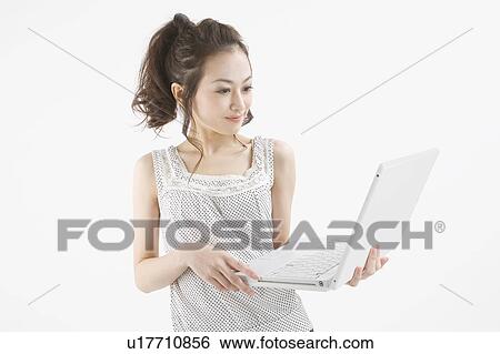 Young woman holding notebook computer View Large Photo Image Stock Photograph - Young woman holding notebook computer. Fotosearch