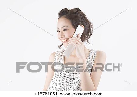 Stock Image - Young woman talking on mobile phone. Fotosearch