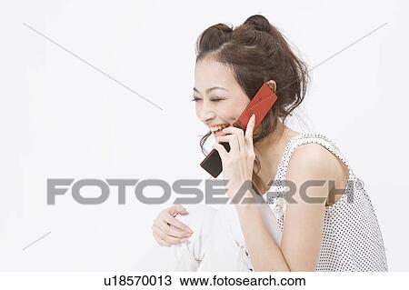 Stock Image - Young woman talking on mobile phone. Fotosearch