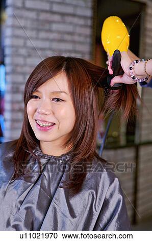 Stock Image - Hairdresser blowing customer's hair with hair dryer, Hair Salon. Fotosearch
