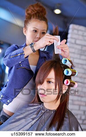 Stock Photo - Hairdresser curling customer's hair, Hair Salon. Fotosearch