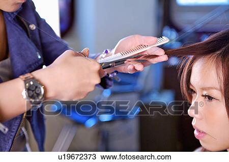 Stock Image - Hairdresser cutting customer's hair, Hair Salon. Fotosearch