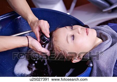 Stock Image - Young woman having her hair washed, Hair Salon. Fotosearch