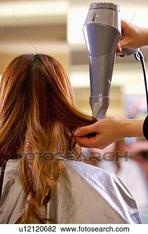 Stock Image - Hairdresser blowing customer's hair with hair dryer, Hair Salon. Fotosearch