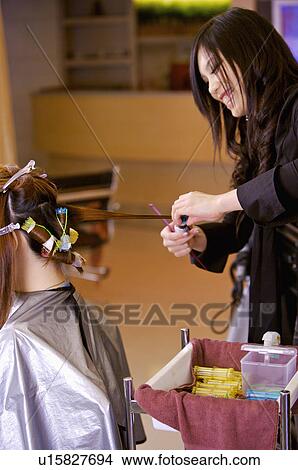 Picture - Hairdresser curling customer's hair, Hair Salon. Fotosearch
