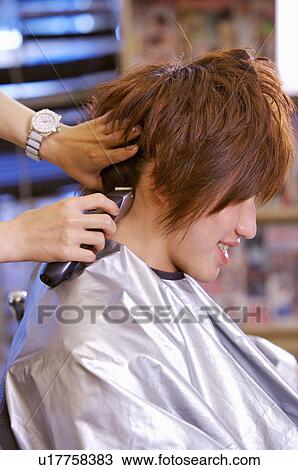 Stock Image - Hairdresser cutting customer's hair, Hair Salon. Fotosearch