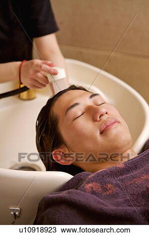 Stock Image - Young man having his hair washed, Hair Salon. Fotosearch