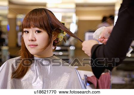 Stock Image - Young woman having her hair curled, Hair Salon. Fotosearch