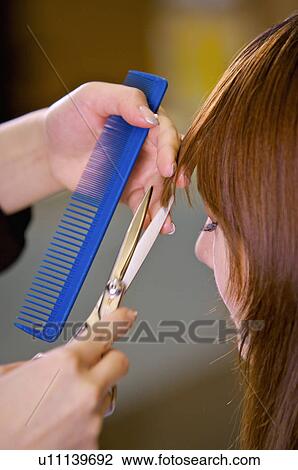 Stock Image - Young woman having her hair cut and closing her eyes, Hair Salon. Fotosearch