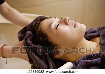 Stock Image - Young woman having her hair washed, Hair Salon. Fotosearch