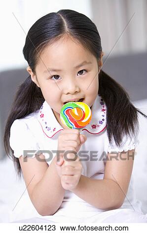 Family, a girl licking her lollipop, Portrait View Large Photo Image Stock Image - Family, a girl licking her lollipop, Portrait. Fotosearch