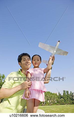 Stock Photograph - Family, father and daughter playing toy airplane in a park. Fotosearch