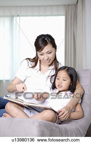 Stock Photograph - Family, mother and daughter reading together. Fotosearch