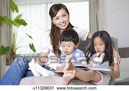 Stock Image - Family, mother together with two children at home, son and daughter reading. Fotosearch