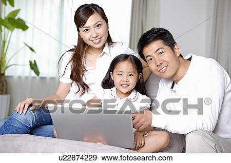 Stock Photo - Family, parents and daughter using a laptop in the living room. Fotosearch