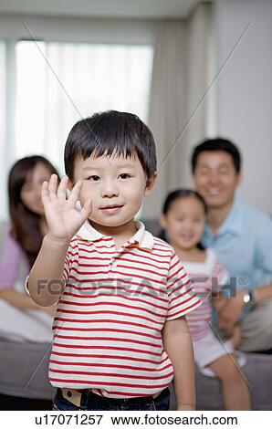 Stock Photo - Family, son greeting, with other families sitting behind. Fotosearch