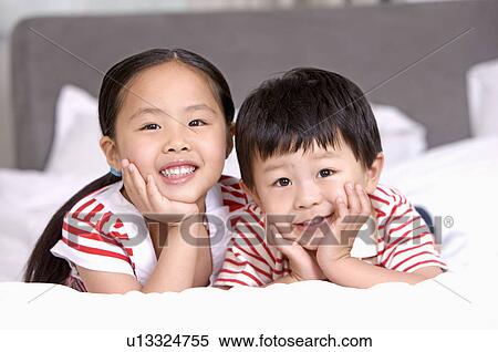 Stock Photography - Family, two children lying on bed. Fotosearch