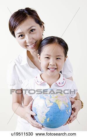 Stock Image - Mother and daughter holding a globe. Fotosearch
