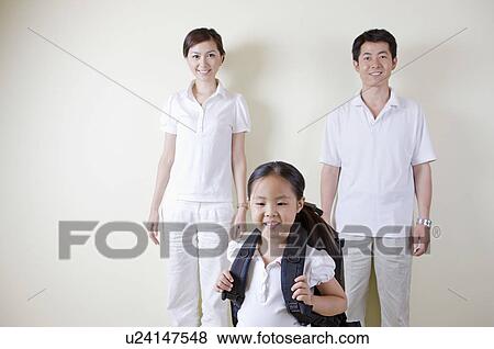Portrait of a Family, daughter carrying a school bag and parents standing behind View Large Photo Image Stock Photo - Portrait of a Family, daughter carrying a school bag and parents standing behind. Fotosearch
