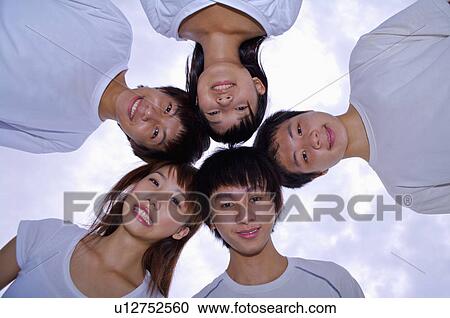 Stock Image - Five teenagers standing and looking down together, Teenager. Fotosearch