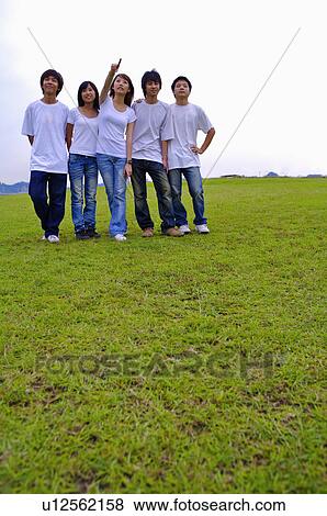 Stock Photo - Five teenagers standing on the lawn together and looking up, Teenager. Fotosearch