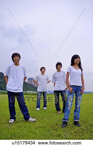 Four teenagers standing on the lawn and looking away, Teenager View Large Photo Image Picture - Four teenagers standing on the lawn and looking away, Teenager. Fotosearch