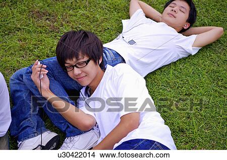 Two boys lying on the lawn and listening music, Teenager View Large Photo Image Picture - Two boys lying on the lawn and listening music, Teenager. Fotosearch