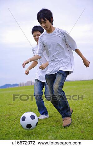 Stock Image - Two boys playing football on the lawn, Teenager. Fotosearch
