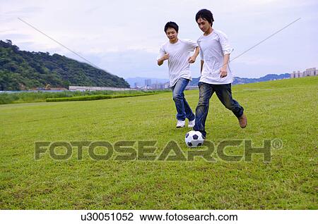 Stock Image - Two boys playing football on the lawn, Teenager. Fotosearch