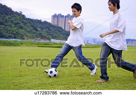 Stock Photograph - Two boys playing football on the lawn, Teenager. Fotosearch