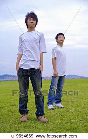Stock Photo - Two boys standing on the lawn and looking away, Teenager. Fotosearch