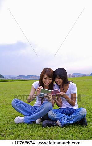 Two girls sitting on the lawn and smiling, Teenager View Large Photo Image Picture - Two girls sitting on the lawn and smiling, Teenager. Fotosearch
