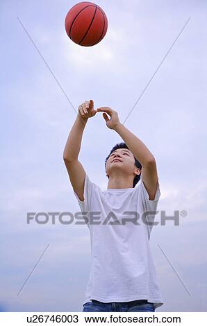 Stock Image - Young boy playing basketball and looking up, Teenager. Fotosearch