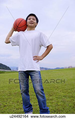 Picture - Young boy standing on the lawn and holding a basketball, Teenager. Fotosearch