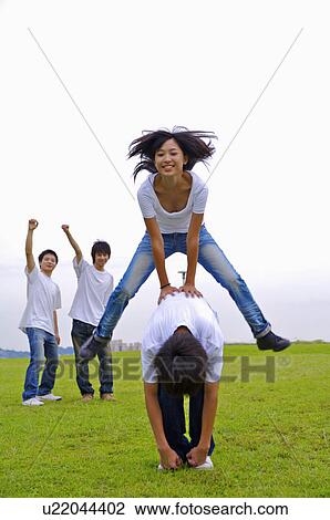 Stock Image - Young girl jumping from young boy and smiling happily, Teenager. Fotosearch