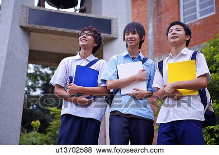 Stock Photo - Teenager boys holding books and looking up together, Teenager. Fotosearch