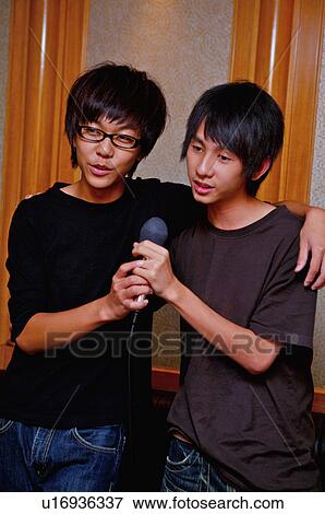 Stock Photo - Teenager boys holding microphone together and singing with hands on shoulder, Teenager. Fotosearch