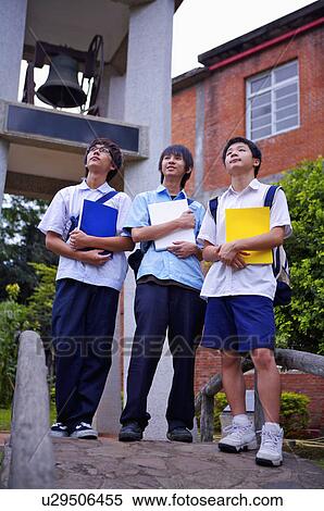 Stock Photography - Teenager boys standing with books and looking up together, Teenager. Fotosearch