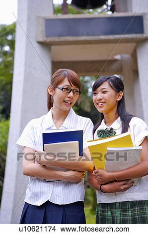 Picture - Teenager girls holding books and smiling happily, Teenager. Fotosearch