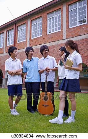 Picture - Teenagers standing on the lawn with a guitar and discussing together, Teenager. Fotosearch