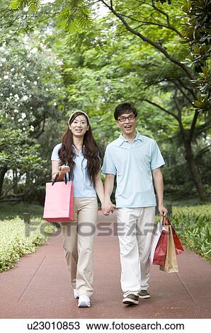 Couple holding hands together and walking on the road with shopping bags, Family, Leisure Activities View Large Photo Image Stock Image - Couple holding hands together and walking on the road with shopping bags, Family, Leisure Activities. Fotosearch