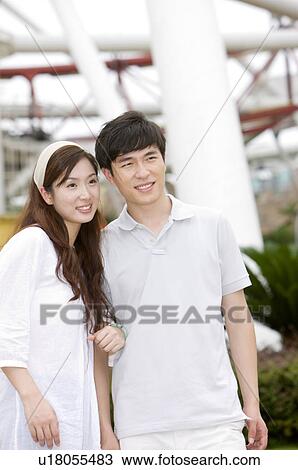 Stock Image - Couple standing together and looking away with smile, Family, Leisure Activities. Fotosearch