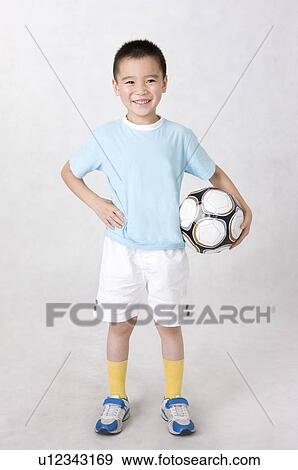 Little boy holding a football with arms akimbo and smiling, Family, Leisure Activities View Large Photo Image Stock Photo - Little boy holding a football with arms akimbo and smiling, Family, Leisure Activities. Fotosearch