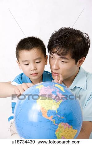 Stock Photo - Little boy looking at a model earth globe with his father, Family, Leisure Activities. Fotosearch