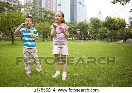 Little girl and boy blowing bubbles on the lawn, Family, Leisure Activities View Large Photo Image Picture - Little girl and boy blowing bubbles on the lawn, Family, Leisure Activities. Fotosearch
