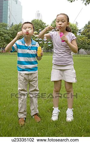 Little girl and boy standing on the lawn and blowing bubbles together, Family, Leisure Activities View Large Photo Image Stock Image - Little girl and boy standing on the lawn and blowing bubbles together, Family, Leisure Activities. Fotosearch