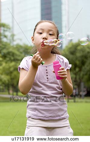 Stock Photo - Little girl standing and blowing bubbles, Family, Leisure Activities. Fotosearch