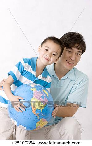 Picture - Man and little boy holding the globe together and smiling at the camera, Family, Leisure Activities. Fotosearch
